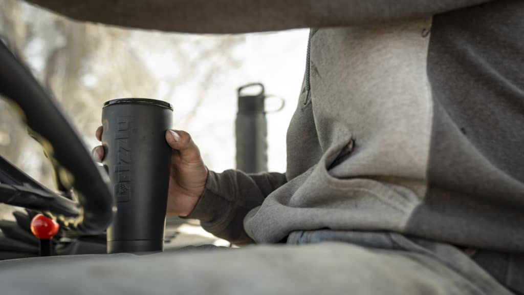 american farmer driving while holding a grizzly grip cup