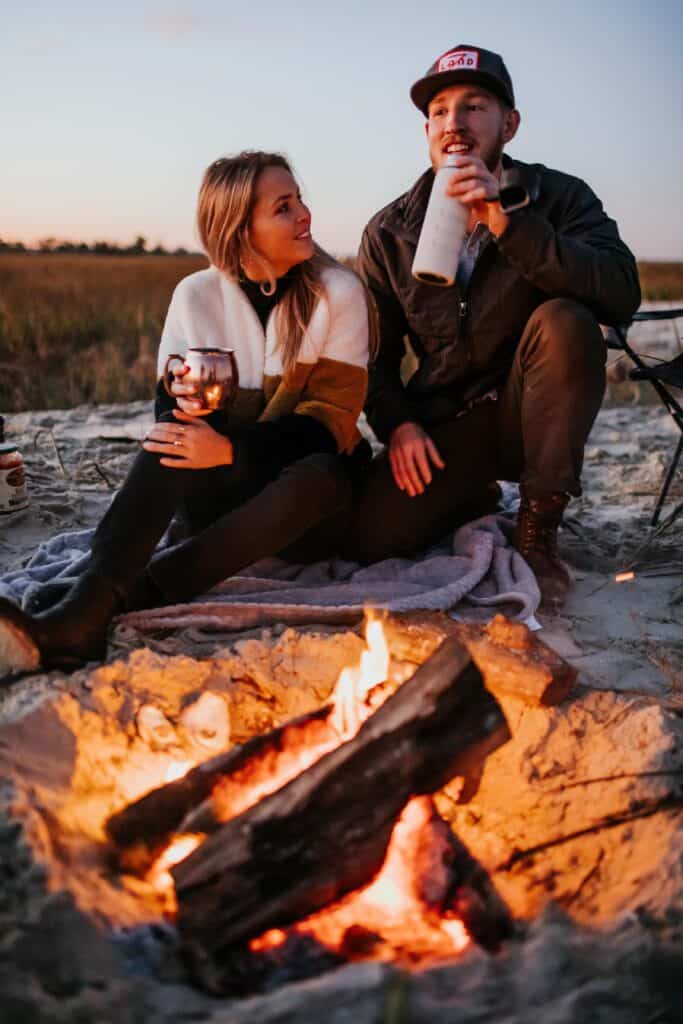 man and woman enjoying a campfire at sunset