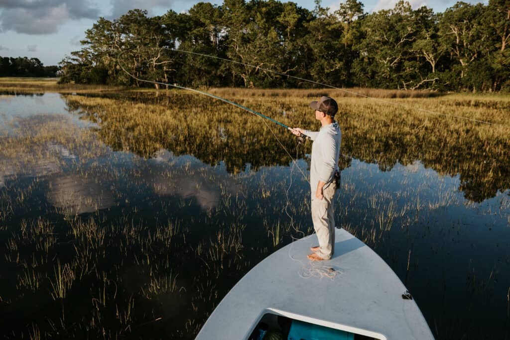 Man standing on bow of boat casting while fly fishing