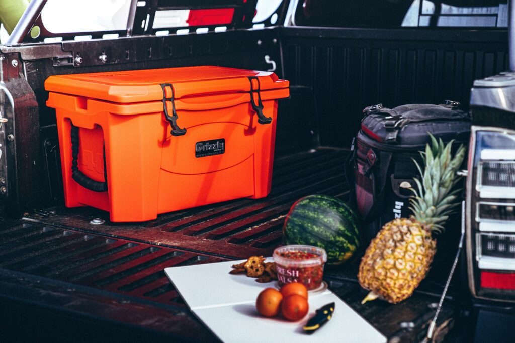 orange grizzly cooler in back of truck with meal prep in foreground