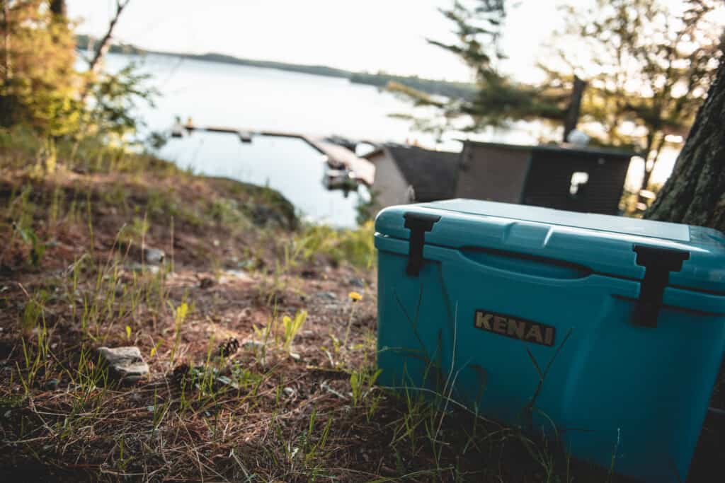 Teal Kenai cooler in foreground with a lake and docks in the background