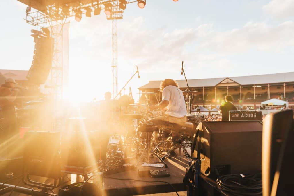 Summer palooza, view from backstage looking at musical group and fans with sunsetting in background